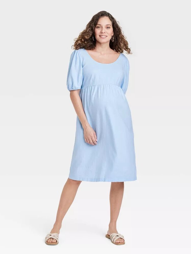Model wears a light blue linen maternity dress. 