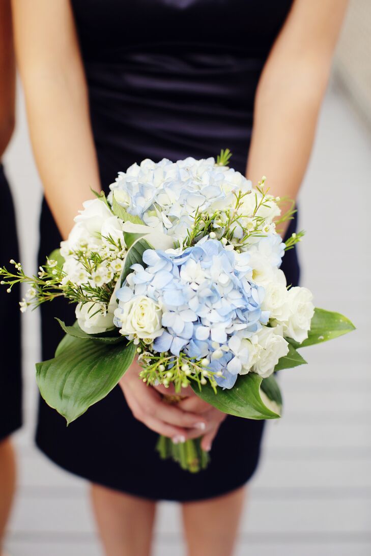 The couple's blue wedding color popped in their flowers. CH Floral Designs arranged bouquets of blue hydrangeas, white roses and greenery to match the navy blue bridesmaid dresses.