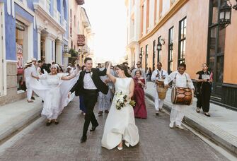 Newlyweds celebrate on a colorful city street with music and dancing. 