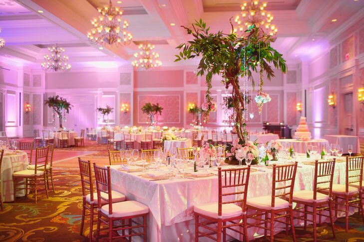 “Our reception décor was designed to feel like an enchanted forest,” Shayna says. The room was lit with a warm pink amber color and the chandeliers were dimmed to create a romantic feel from the candles.