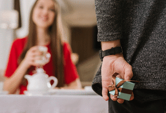 Person hiding engagement ring box