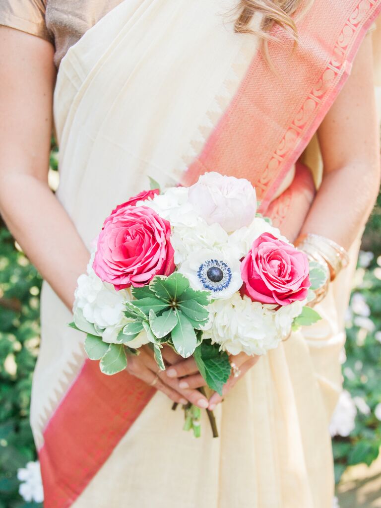 A bridesmaid holds a bright pink and white bouquet.