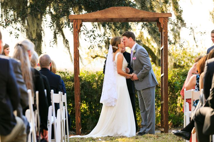 Amanda and Ben exchanged vows under a simple wooden wedding arbor during their waterfront reception. They loved having the creek and lush, moss-covered trees as the gorgeous backdrop. Since the venue was stunning enough to stand on its own, the couple kept decor to a minimum with a simple wooden arbor and white folding chairs.