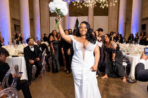 Bride in Fitted Gown With Deep V-Neckline, Guests Behind Her About to Throw Her White Bouquet