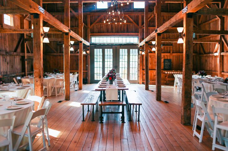 The Barn at Flanagan Farm in Buxton, Maine, offered a refined wooden interior with exposed wooden beams provided a rustic setting where guests dined and danced the night away. A wooden farm head table ran through the center of round dining tables set with white linens and folding chairs. Chandeliers added an elegant ambience.