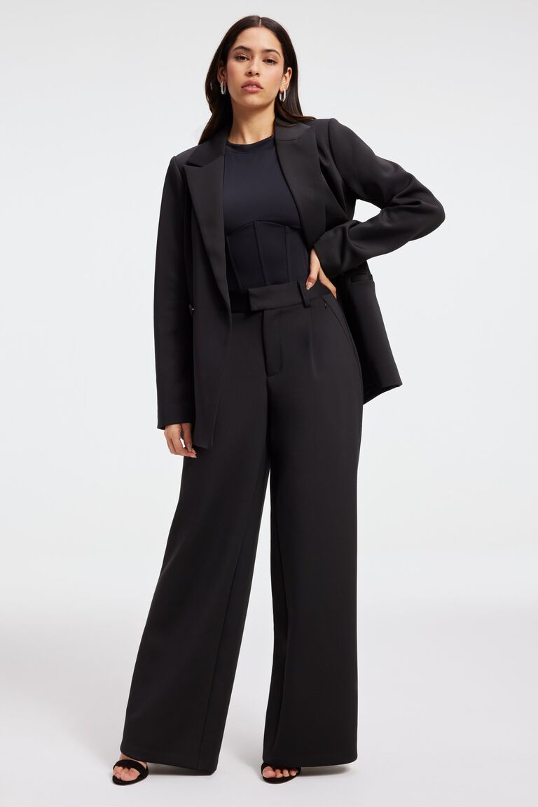 Model wears a fitted black pantsuit. 
