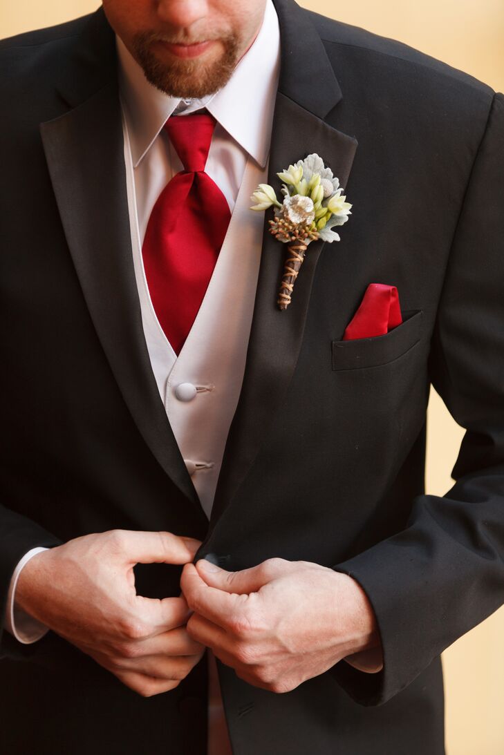 The groom wore a classic black tuxedo on the wedding day, with a white vest and bright red tie underneath. A red pocket square and an ivory boutonniere accented the jacket.