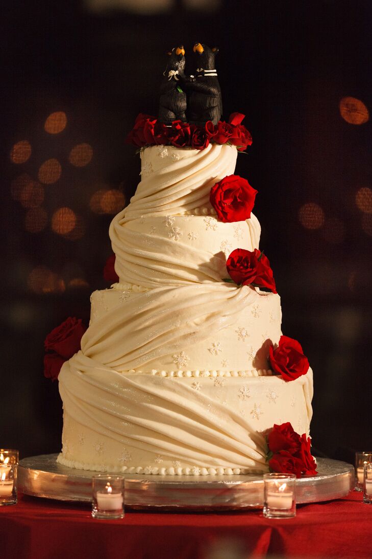 “The four-tiered wedding cake was designed to complement the themes of the wedding, with white icing, white draping, subtle shimmer over the whole cake and small snowflakes on each layer,” says Karen. “The florist added red roses cascading down two sides of the cake, as well as surrounding the cake topper, which was a black bear couple in wedding attire, a tribute to the bride's love for bears.”