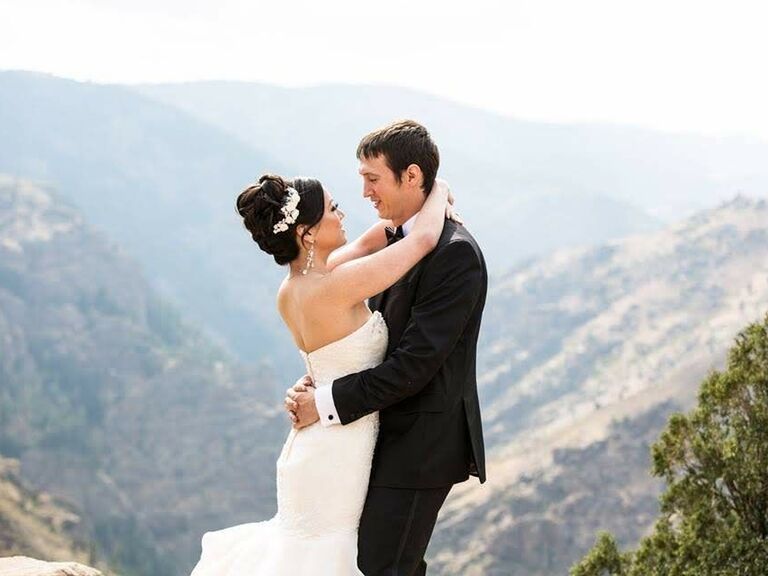 Bride and groom embrace surrounded by mountains in Colorado.