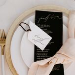 winter wedding place setting with gold charger plates and flatware, black menu card and blush linen napkin