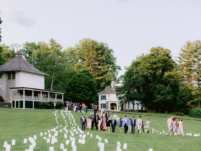 Wedding guests walking through paper lantern pathway at outdoor summer wedding