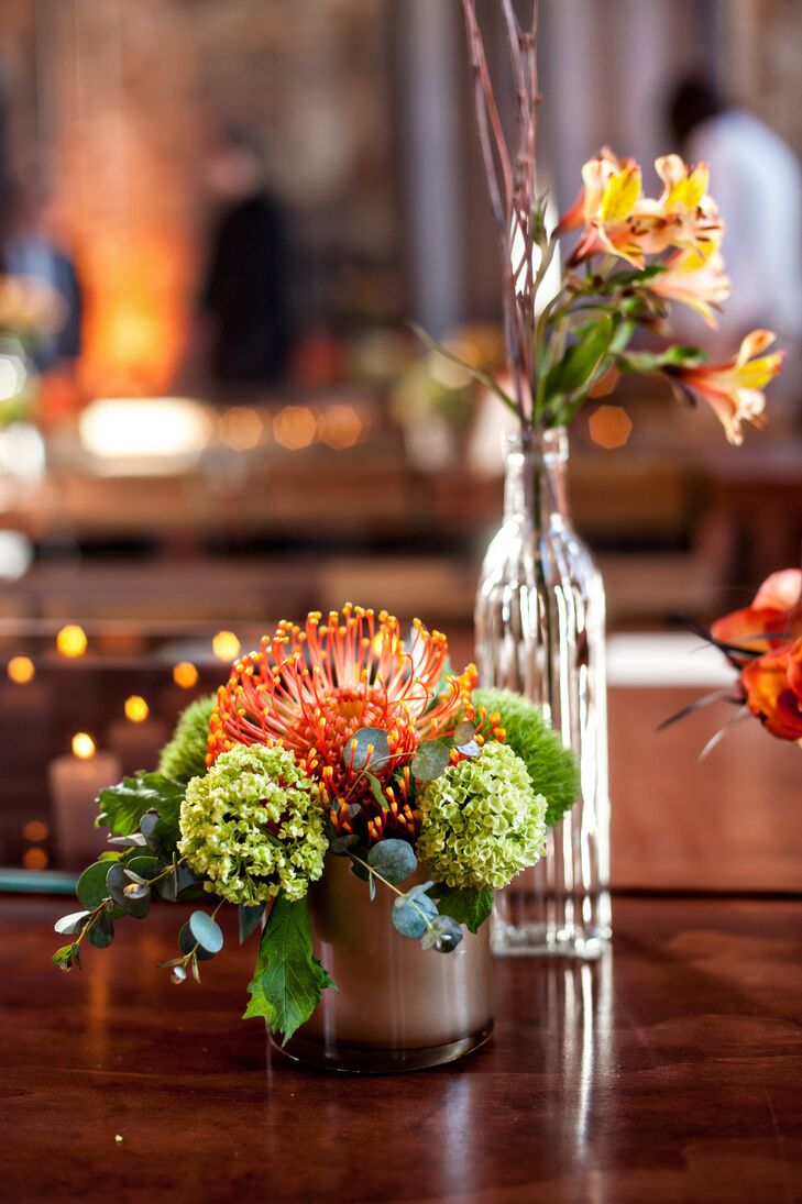 On reception tables, green and orange succulent arrangements as well as lilies mixed with branches in a glass bottle served as centerpieces.