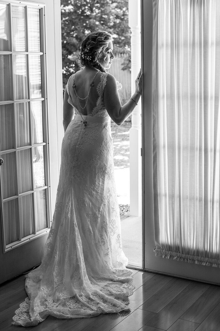 Meagan wore a lace wedding dress with a plunging back by Marisa Bridals, which she bought at Betsey Robinson's Bridal Collection. To accentuate the plunging back of her lace wedding dress, she accessorized with a back necklace with white and blue beads. She wore her hair in a side-swept braid with baby's breath. She also wore an ivory sash to complete the look.
