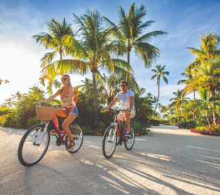 couple biking in front of palm trees in the Florida Keys