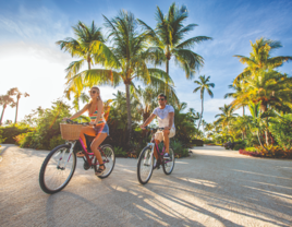 couple biking in front of palm trees in the Florida Keys