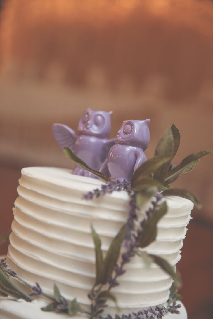 Jessica and Joel served a simple white wedding cake with buttercream frosting and amaretto cake. The classic design featured sprigs of lavender and a purple owl cake topper to complement the wedding theme.