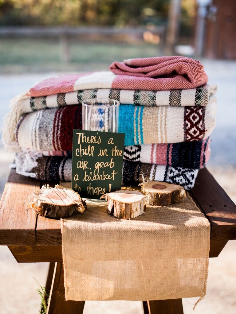 Cozy and stylish blankets stacked and ready to be used by guests during the wedding ceremony. 