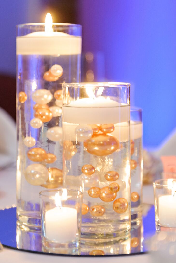 The centerpieces included vases of varying heights filled with gold and white pearls and topped with floating candles.