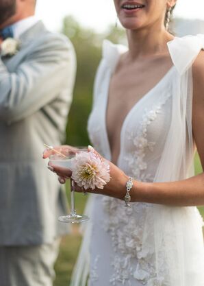 Bride in Plunging Neckline Gown Holding Drink in Coupe Glass and a Pink Flower