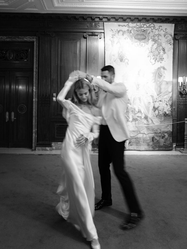 Kate Bock dances with her husband in a white gown at her wedding reception. 