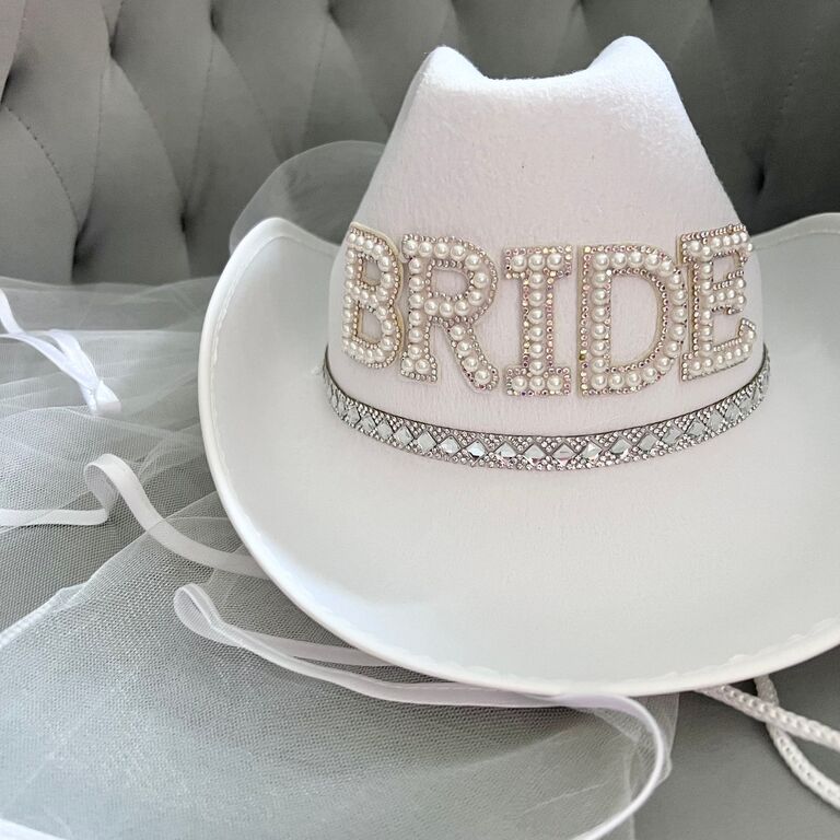 A white cowboy hat with rhinestone detailing and pearl bedazzled 