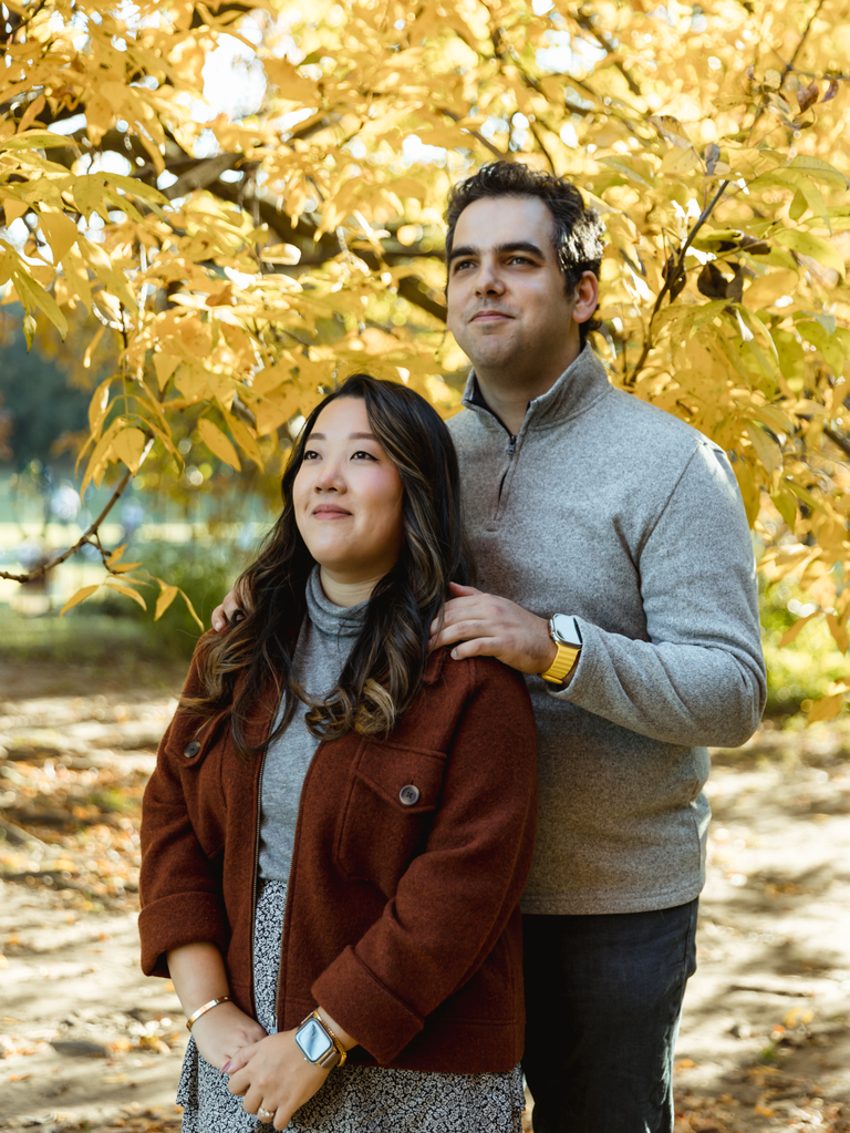 Couple stares off into the distance white their photographer snaps a photo. 