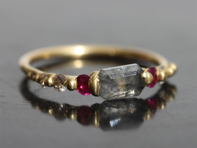 Gray cushion cut diamond with ruby side stones and small diamonds on gold band