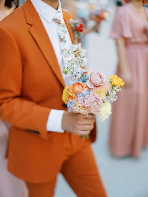 Bride's Bridesman in an Orange Suit Carrying a Small Bouquet With Pastel Flowers