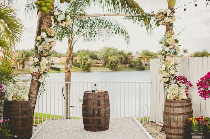 The wedding arch brought Florida’s palm trees into their ceremony! Each tree was connected by one strand of birch wood and covered with tons of flowers. White, green and pink hydrangeas, white roses, greenery and baby’s breath accented each one. Wooden barrels on both sides were also topped with similar arrangements.