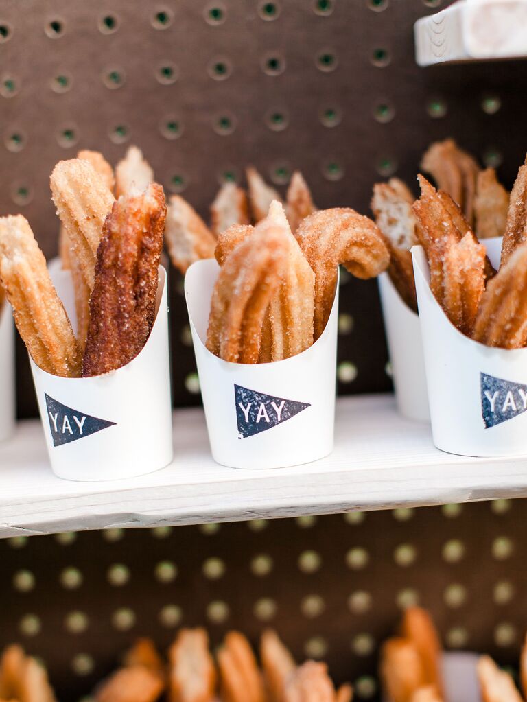 churro wedding favors in to-go cups decorated with yay in blue triangle