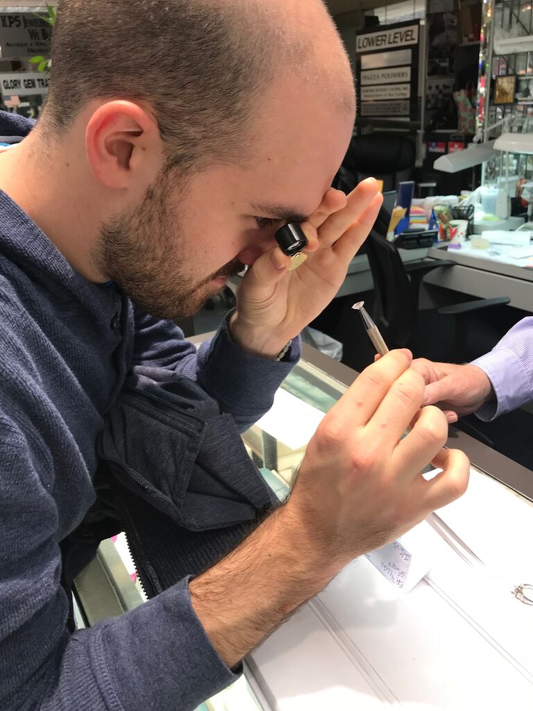 man looking at diamond with magnifying glass