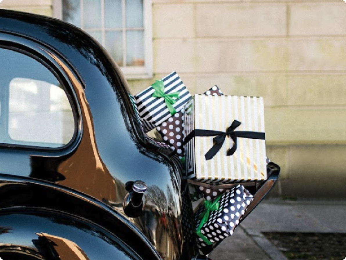 Festively wrapped gifts in the trunk of an antique car.