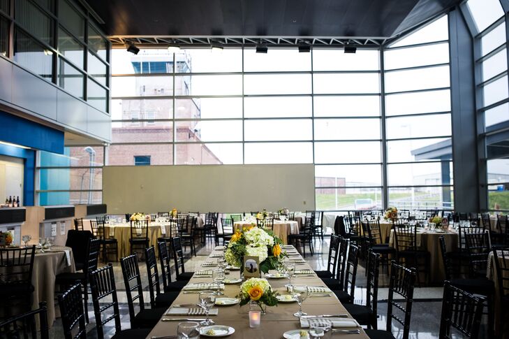 The couple transformed this regional airport setting into an elegant ballroom with long tables, dark Chiavari chairs and bright centerpieces.