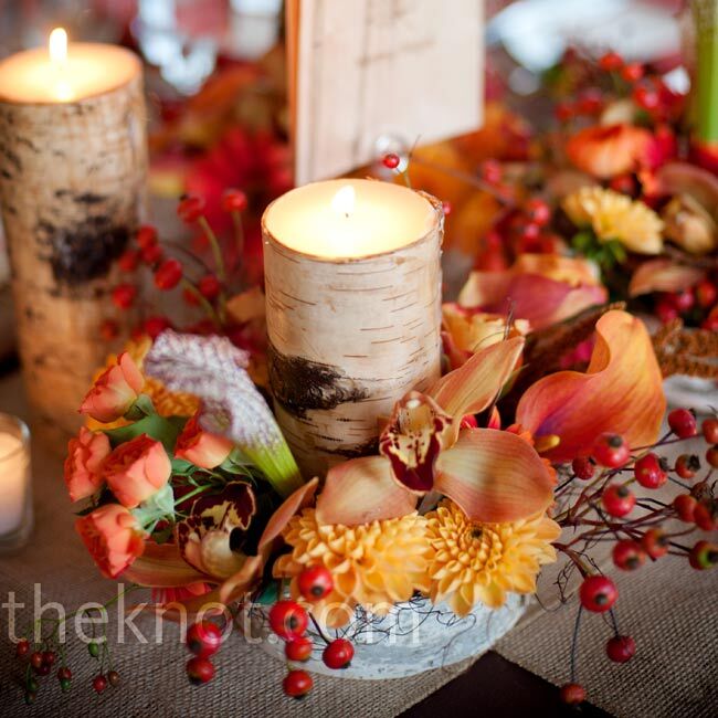 For a rustic look, the centerpieces included birch-bark containers and votive candles surrounded by a mix of orange and red flowers.