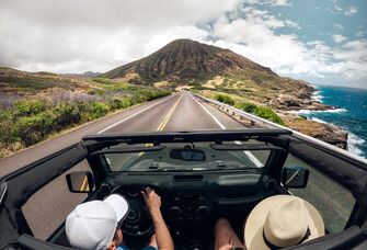 People in a jeep driving on the road.