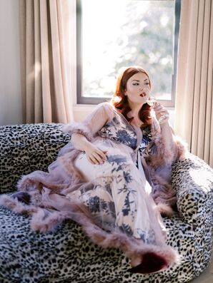 Bride in Sheer, Lavender Robe With Feathers Sips Champagne While Getting Ready