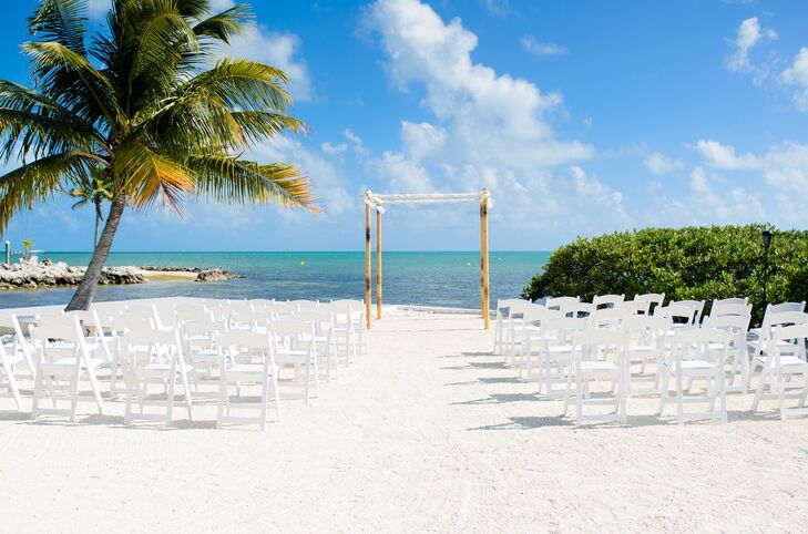 The couple decorated their ceremony with rows of white chairs and a simple bamboo arch wrapped in white fabric.