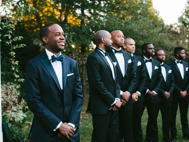 Groom smiling with groomsmen watching during wedding ceremony