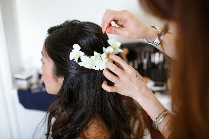 Eriko’s hair was styled in a half-up, half-down look, embellished with white orchid flowers for a whimsical, romantic feel.