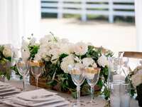 white floral and greenery centerpiece in low wooden rectangular trough