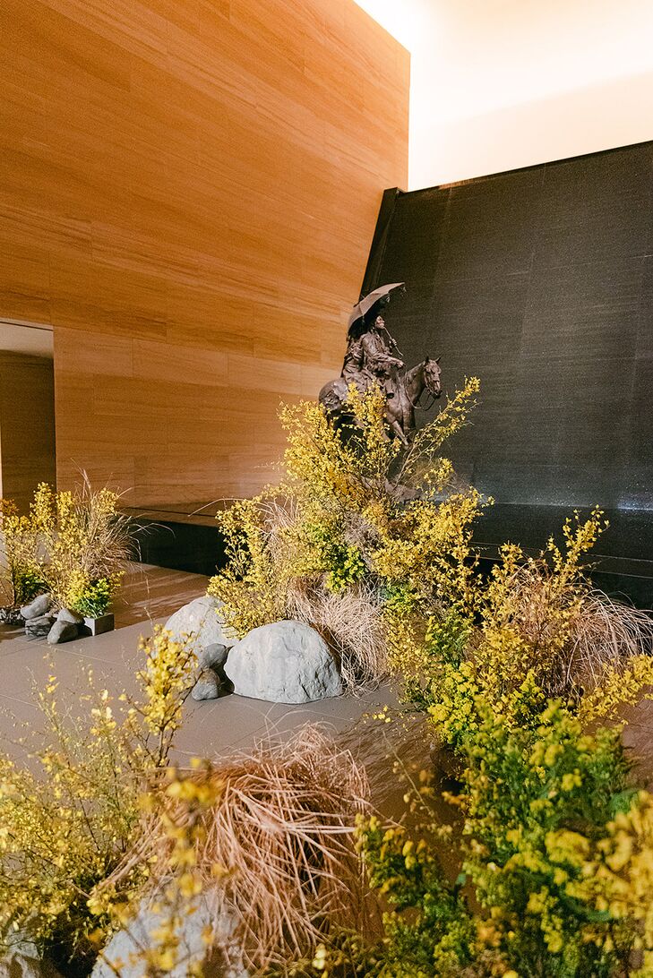 A modern, art-inspired ceremony altar at a museum with minimalistic decor and arrangements of yellow flowers and greenery over faux rocks for a sophisticated and alternative wedding.