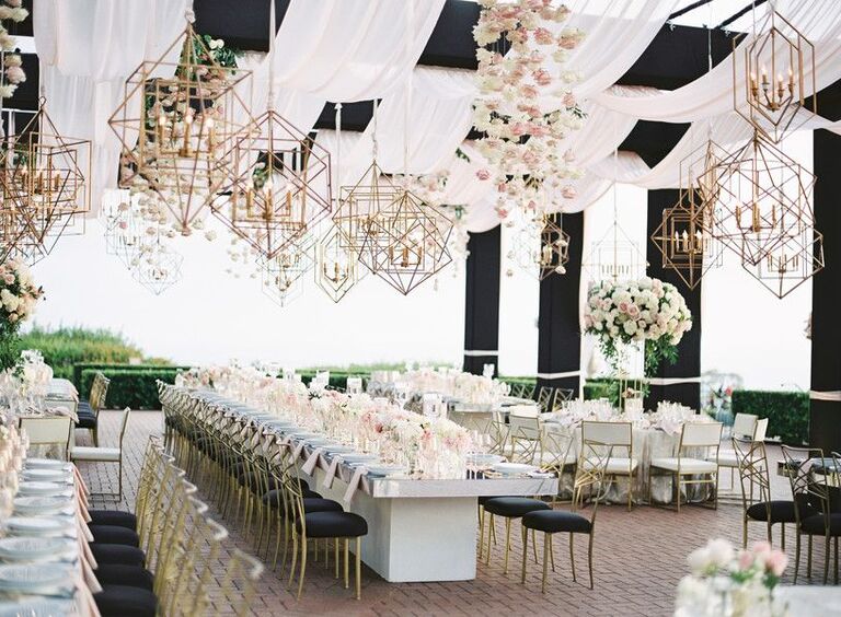 Al fresco wedding reception with gold chandeliers and glam black-and-white details