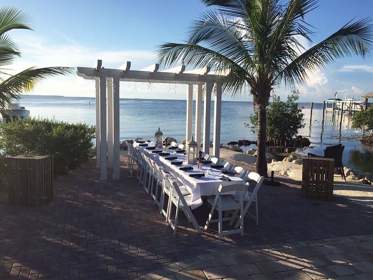 View of an outdoor table set for an event with a pergola and palm trees at Marker 88 in Islamorada Florida 