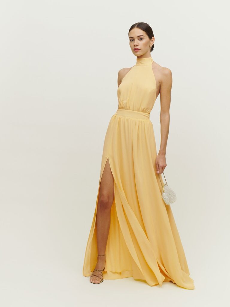 Model wears a butter-yellow gown with a halter neckline. 