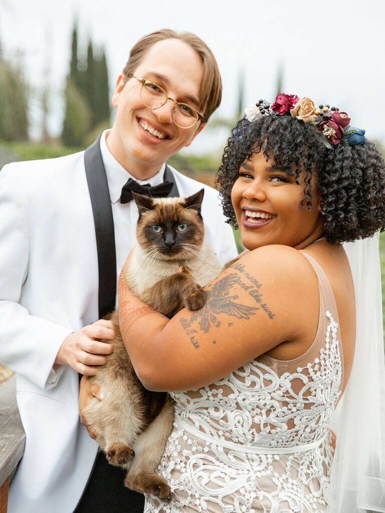 Couple poses on their wedding day with their cat. 