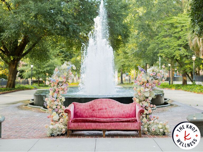 Couch surrounded by flowers in front of fountain
