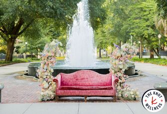 Couch surrounded by flowers in front of fountain