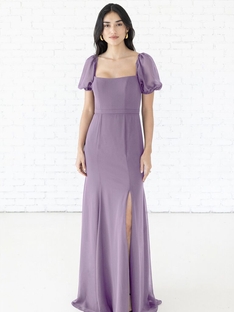 Model wears a sheer purple gown with puffed sleeves. 