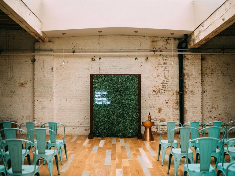modern indoor wedding arch alternative with neon sign against boxwood wall