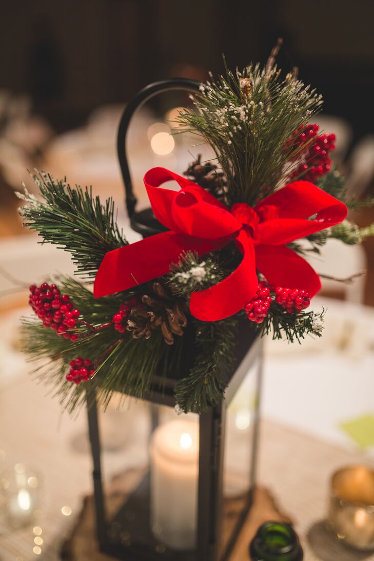 Elizabeth and Mason's lantern centerpieces were adorned with pine, red berries and red ribbons following the Christmas-themed wedding day.